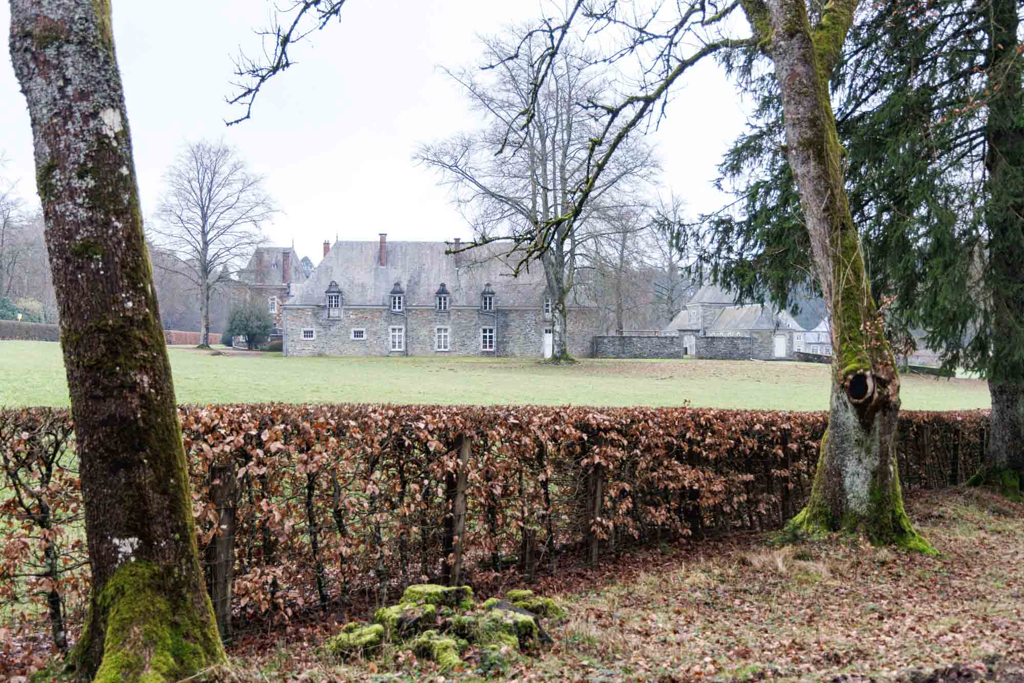Kasteel van Roumont achter een haag en bomen in de winter