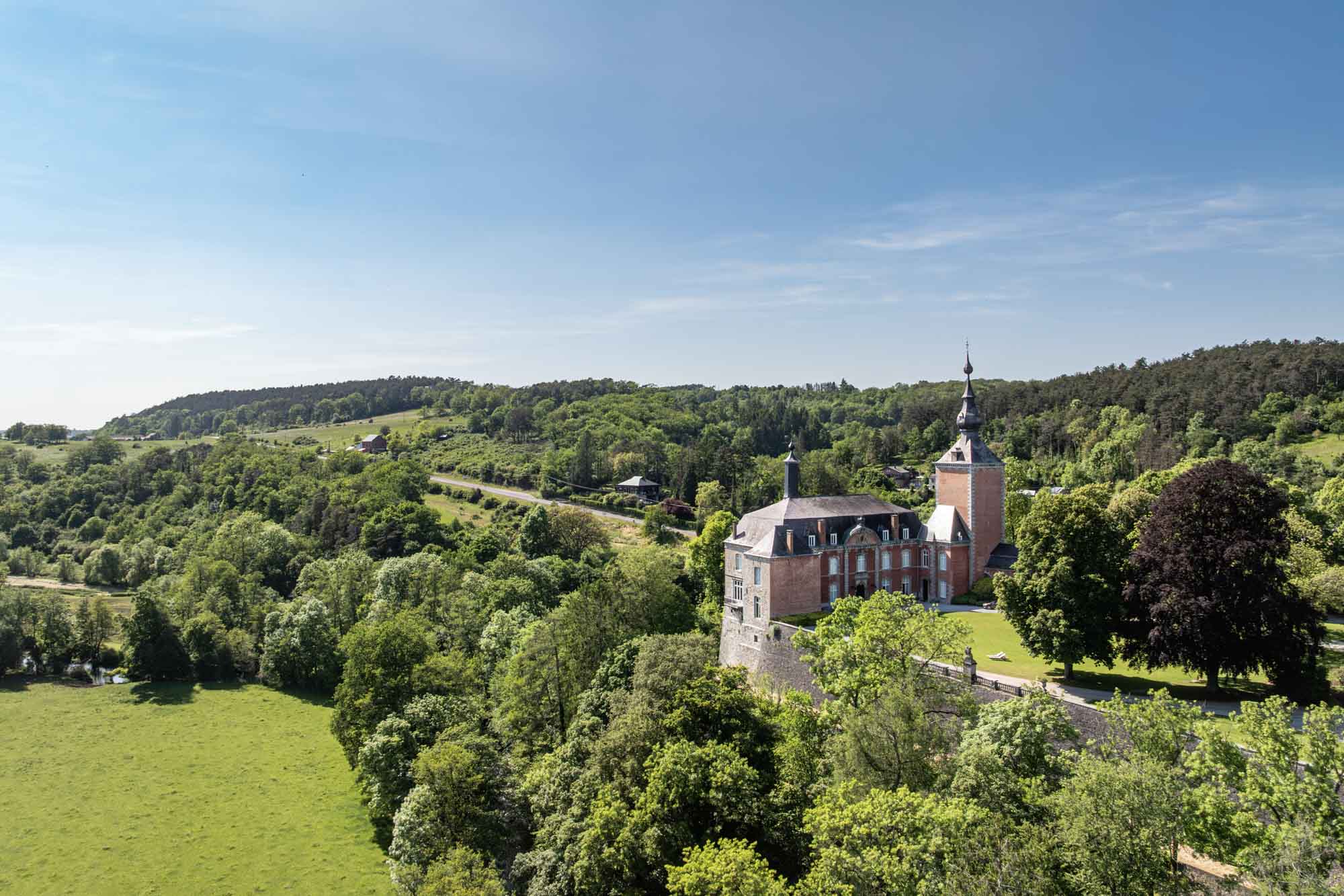 Vierves-sur-Viroin avec son château et ses maisons en pierre dominant une vallée verdoyante au printemps.